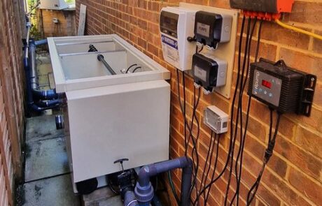 A high-performance drum filter system installed next to a koi pond, automating waste removal and filtration.