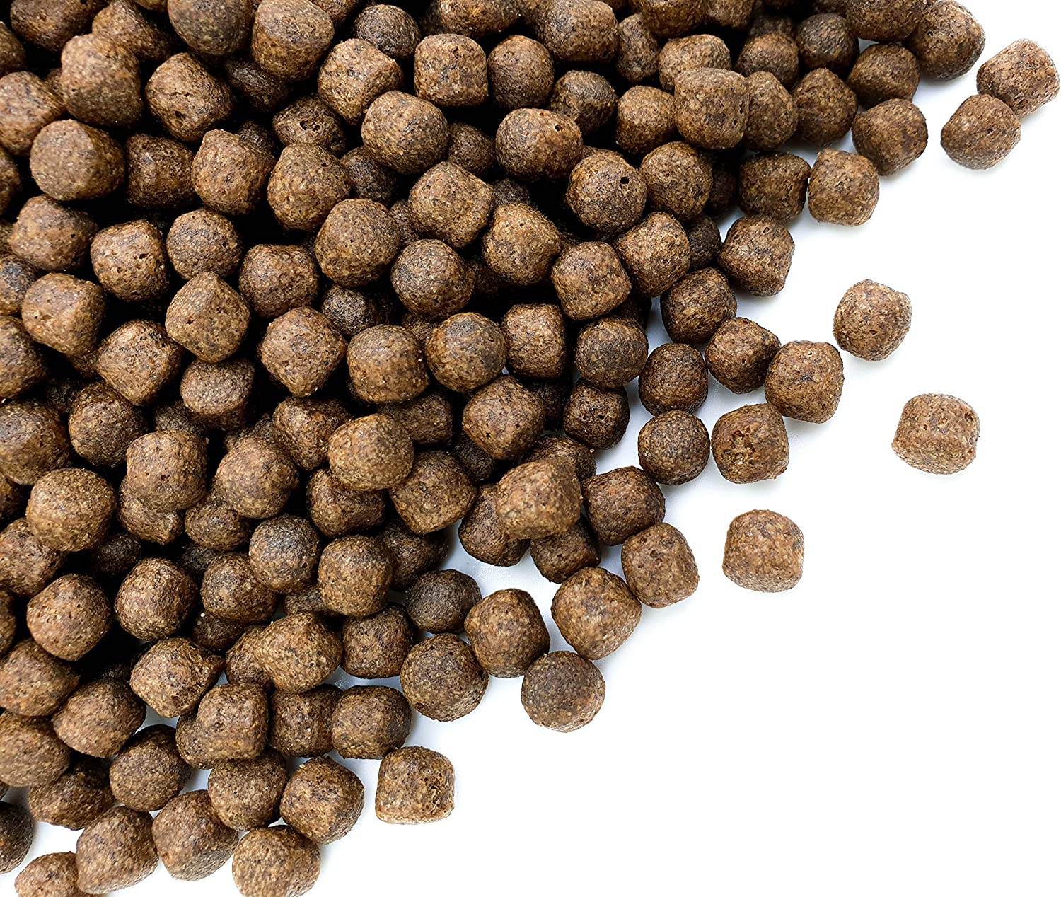 Brown koi food pellets on a white background