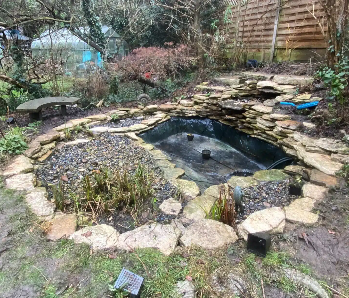 A beautifully maintained pond with trimmed plants, clean rocks, and clear water after expert pond cleaning in London.