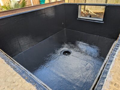 A newly completed koi pond with a smooth, watertight fibreglass finish and insulated walls, ready to be filled with water.