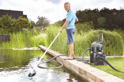 A pond hoover removing debris from the bottom of a garden pond, enhancing water clarity and health.