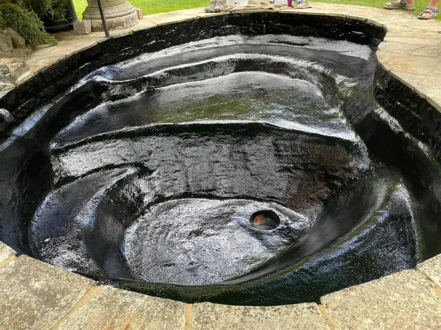 A completed pond featuring a sleek and durable fibreglass lining with a black gel-coat finish.