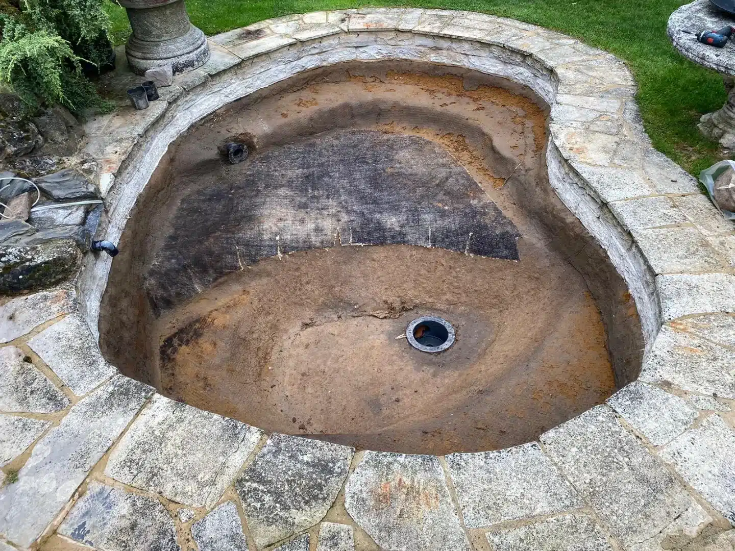 The pond after the old liner has been carefully cut out, revealing the underlying structure.