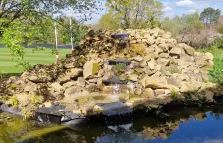 Large Natural-Looking Rock Waterfall Built by That Pond Guy in London A striking large waterfall constructed using natural rocks, built by That Pond Guy in London to create a stunning, natural water feature.