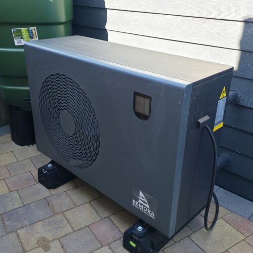 Remora Professional inverter heat pump installed beside a koi pond with connected filtration pipework