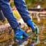 Oase blue neoprene pond gloves being used beside a garden pond