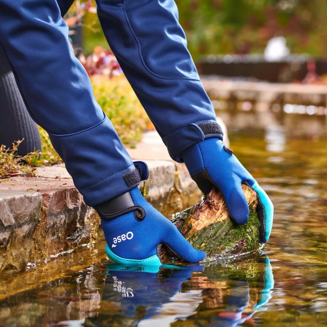 Oase blue neoprene pond gloves being used beside a garden pond